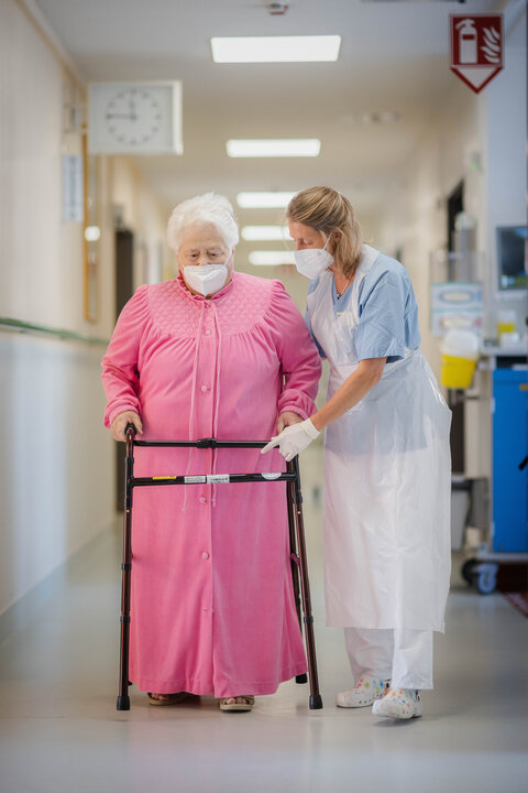 Physiotherapeutin Ulrike Irmer begleitet eine Patientin an der Gehhilfe