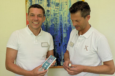 Spricht für das KRH Klinikum Lehrte beim 1. Myofaszialen Schmerzsymposium der DIPLOMA Hochschule: Ingo Volker Rembitzki (rechts) im Bild mit Dr. Emanuel Strüber. Dr. Strüber zeigt das Analysegerät Myoton, mit dem Gewebesteifigkeit und Elastizität gemessen werden, Rembitzki Microneedling Dermaroller zur medizinischen Anwendung und Behandlung von Narbengewebe.