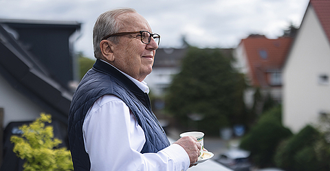 Opa trinkt Kaffee auf Balkon