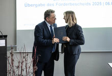 Der Minister übergibt den Förderbescheid an Frau Schulte.