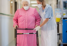 Physiotherapeutin Ulrike Irmer begleitet eine Patientin an der Gehhilfe