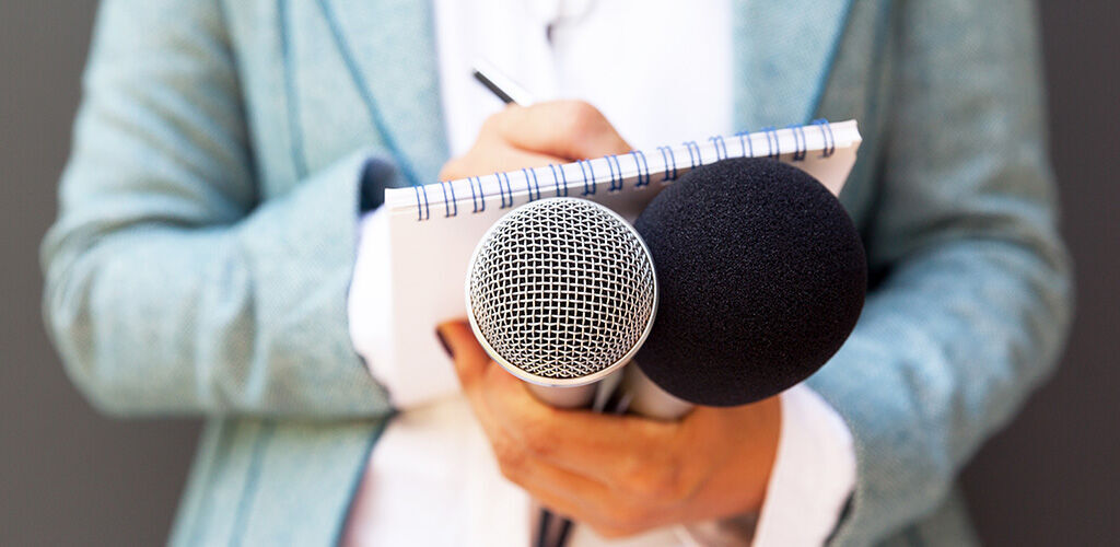 Journalistin mit Block und Mikrofon