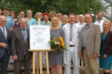 Übergabe im Klinikpark: Dr. Martin Memming (links) und Marit Neels (Mitte) nehmen stellvertretend für alle Beschäftigten des Klinikums Neustadt am Rübenberge das Zertifikat entgegen.