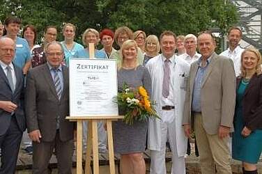 Übergabe im Klinikpark: Dr. Martin Memming (links) und Marit Neels (Mitte) nehmen stellvertretend für alle Beschäftigten des Klinikums Neustadt am Rübenberge das Zertifikat entgegen.