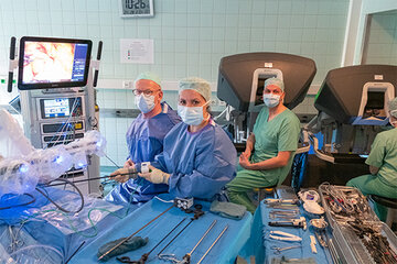 Links sind die Arme des Roboters zu sehen. Gesteuert werden sie von Dr. Heiko Aselmann (r.), Oberarzt der Klinik für Klinik für Allgemein-, Viszeral- und Gefäßchirurgie am KRH Klinikum Robert Koch Gehrden. Assistiert wird ihm von Dr. Martin Memming, Chefarzt der Klinik und Simona Galante, Operationstechnische Assistentin am KRH Klinikum Robert Koch Gehrden.